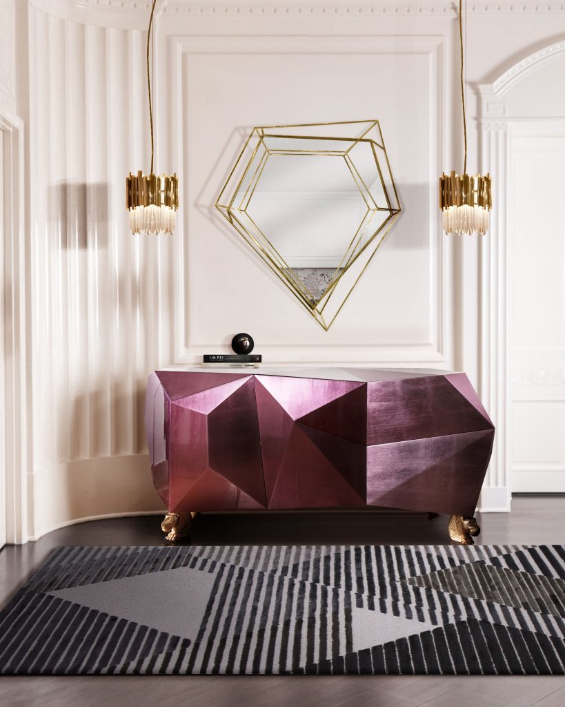 hallway with black and grey rug, triangular miror, two golden suspension lamp and a pink sideboard