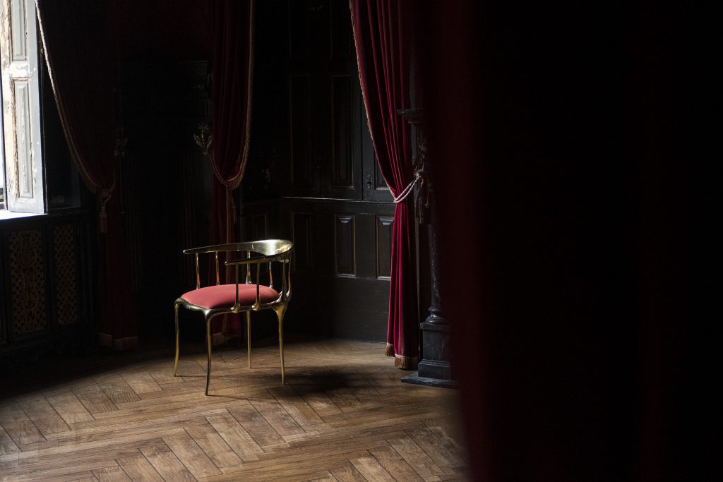 Intimate Luxury: Nº11 Chair, red fabric and gold finishes. Red curtains and wooden floor.